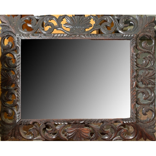 1012 - A Victorian carved and dark stained oak mirror, the rectangular bevelled plate in splayed frame of l... 