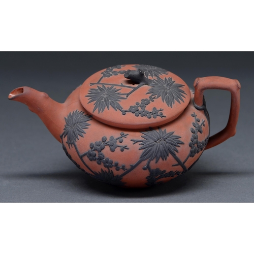 474 - A Wedgwood Rosso Antico teapot and cover, c1820, ornamented in black stoneware with prunus and bambo... 