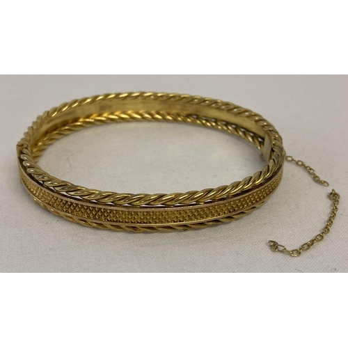 17 - A gold bangle with diamond shaped decoration to centre and twisted rope details to both edges.  Safe... 