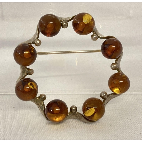 1036 - A modern design silver and amber brooch. Circular design with fluted edge detail set with 8 round ba... 