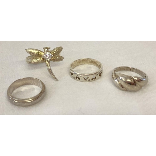 1042 - 4 silver and white metal dress rings. Comprising: band ring, a dragonfly ring set with a clear stone... 