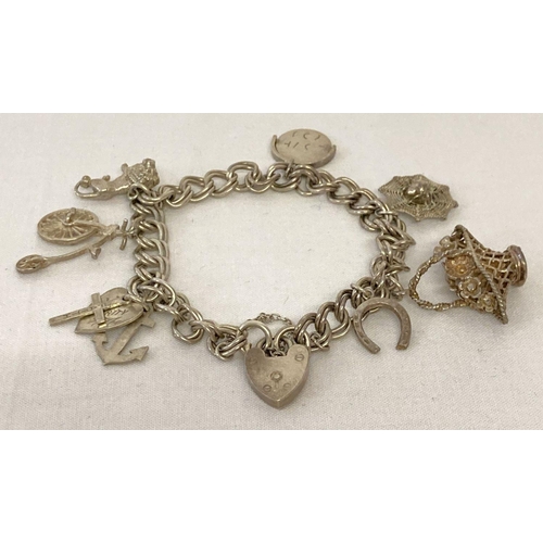 1046 - A vintage double curb chain silver charm bracelet with padlock clasp, safety chain and 7 charms. Hal... 