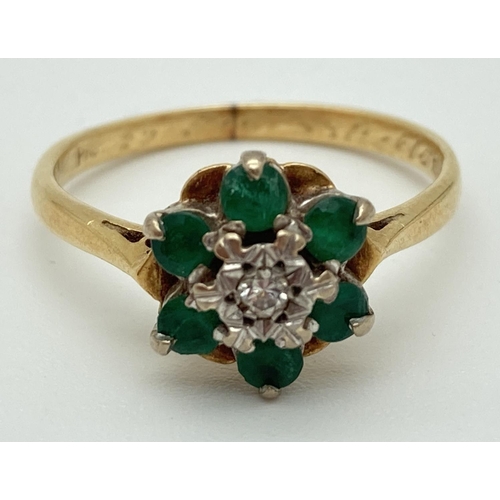 1008 - An 18ct gold, emerald and diamond ring set with flower shaped cluster. Central diamond surrounded by... 