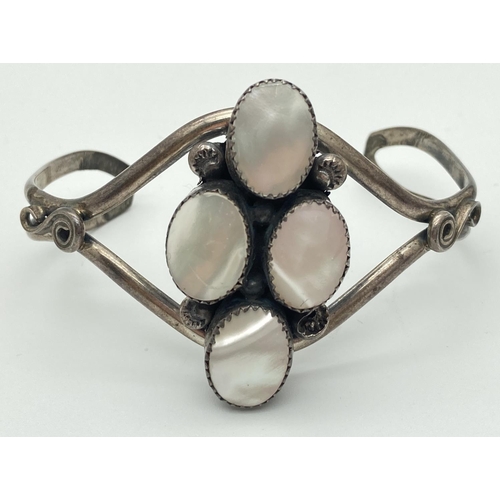 1054 - A white metal open style cuff bangle set with 4 oval pieces of mother-of-pearl.
