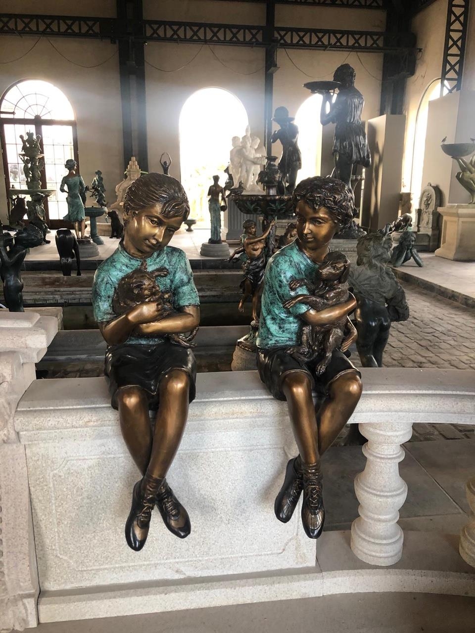 EXCEPTIONAL PAIR OF CAST BRONZE STATUES DEPICTING BROTHER AND SISTER HOLDING PUPPIES