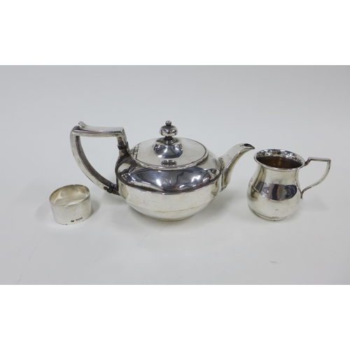 62 - Georgian silver teapot, London  1807, George V silver cream jug , London  1921 and a silver napkin r... 