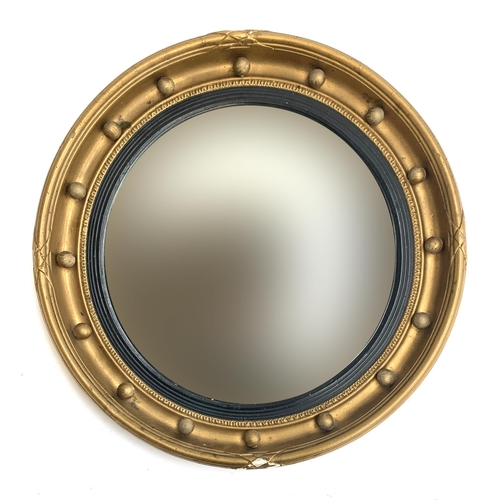 A 20th century regency style convex circular mirror with ebonised reeded slip and bobble moulding, 49cmD