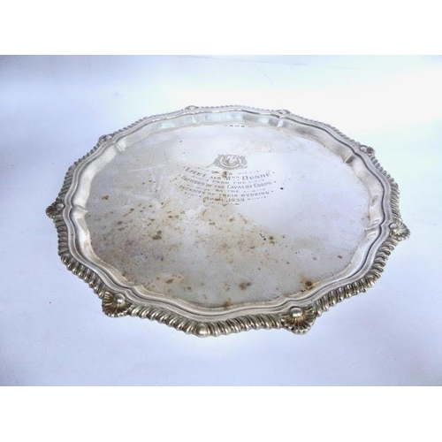 8 - Silver salver of shaped circular form, with gadroon and shell border, On three bun feet with present... 