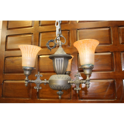 12 - Polished metal three branch chandelier with orange glass shades {40 cm H x 50 cm Dia.}.