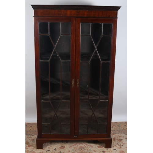 3 - A GEORGIAN MAHOGANY BOOKCASE the dentil moulded cornice above a pair of astragal glazed doors contai... 