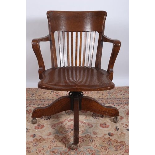 5 - A VINTAGE OAK SWIVEL OFFICE CHAIR the curved top rail with pierced splats with scroll arms with shap... 