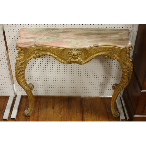 17 - A CONTINENTAL CARVED GILTWOOD CONSOLE TABLE of serpentine outline surmounted by a veined marble top ... 