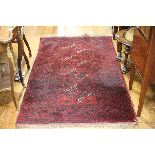 55 - A TRIBAL RUG the central panel filled with serrated hooks stylized flowerheads and foliage within a ... 