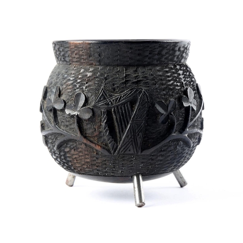 44 - A carved bog oak cauldron, the body relief-carved with trailing shamrock, wolfhound and harp, on thr... 