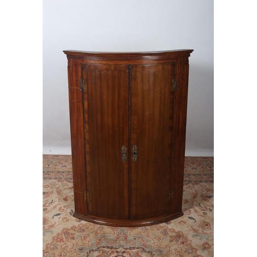 45 - A GEORGIAN MAHOGANY CROSS BANDED HANGING CORNER CUPBOARD the moulded cornice above a pair of panelle... 