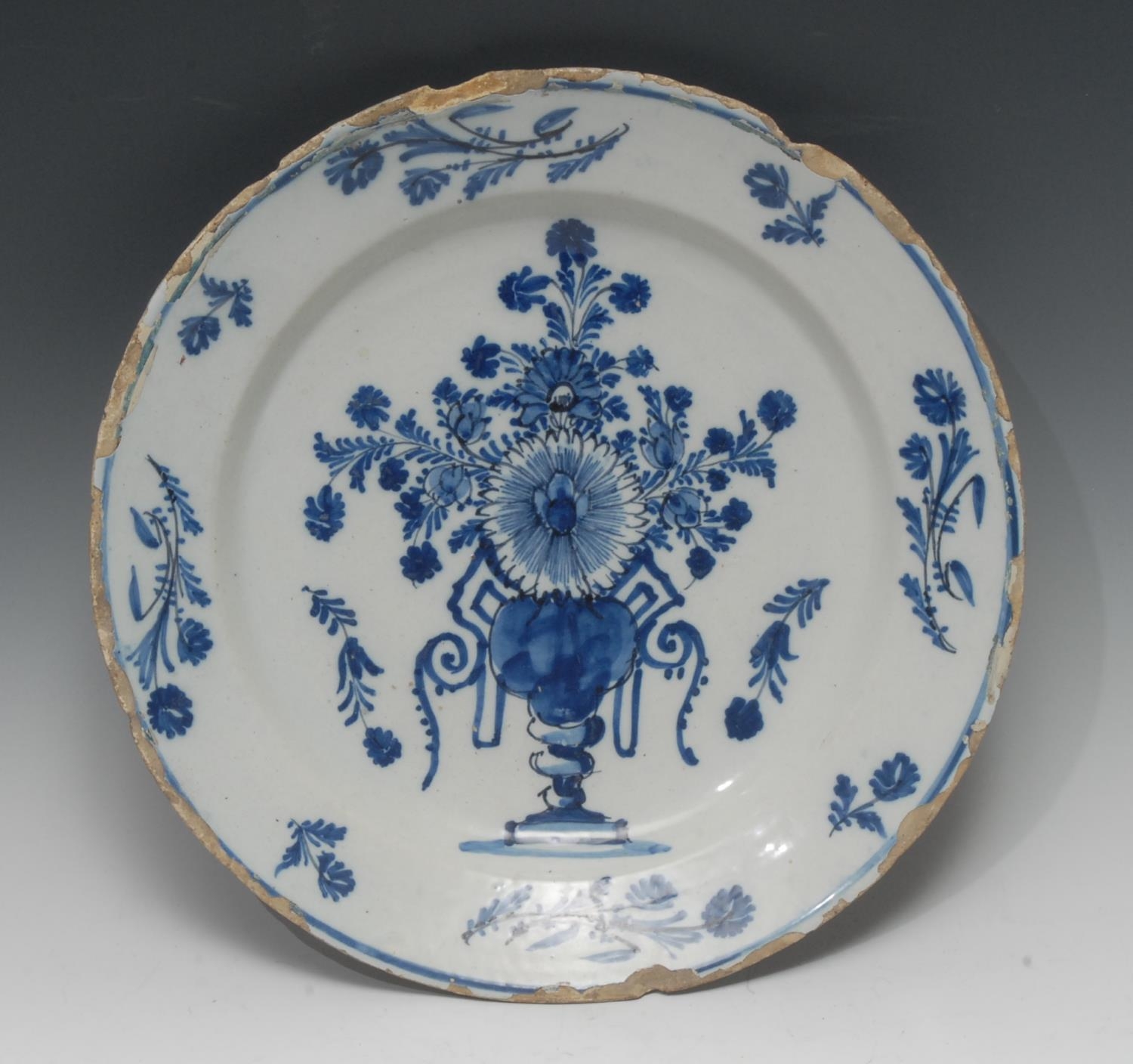 An early 18th century English Delft circular charger, painted in underglaze...