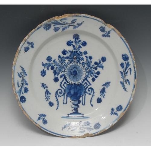 42 - An early 18th century English Delft circular charger, painted in underglaze blue with a Baroque stil... 