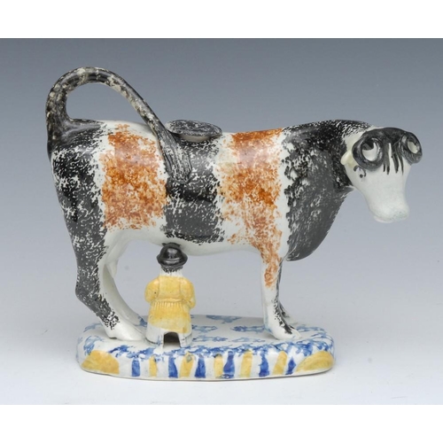 10 - A 19th century Pearlware cow creamer, possibly Yorkshire, standing four square, sponged in black and... 