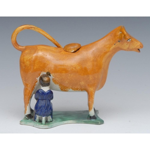 3 - A 19th century cow creamer and cover, standing four square, with milkmaid, in tan, flat shaped plint... 