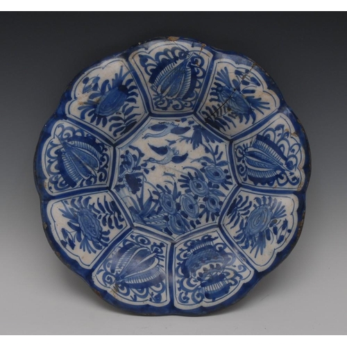 21 - An early 18th century Delft fluted shaped circular charger, painted in tones of blue and white with ... 