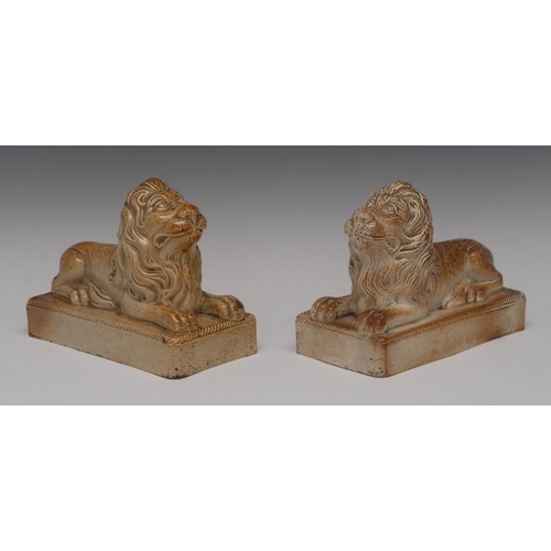24 - A pair of  Brampton brown salt glazed stoneware models of a recumbent lions, rectangular bases, rope... 