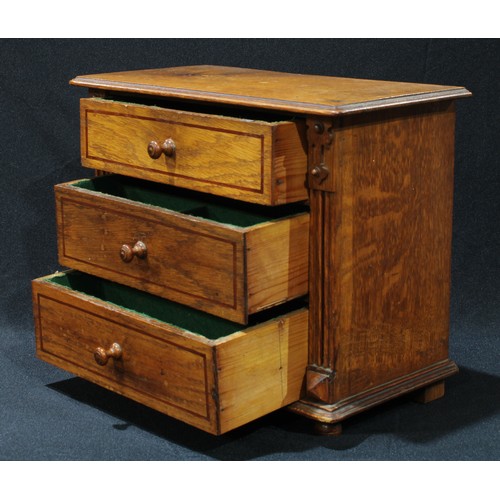 42 - An early 20th century oak miniature chest of drawers, oversailing rounded rectangular top above thre... 