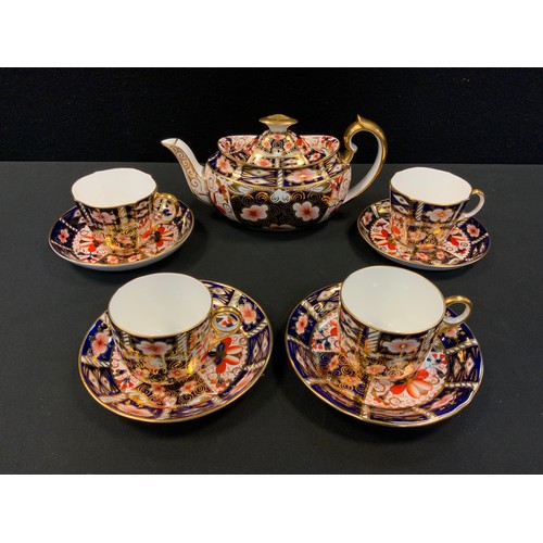 22 - A Royal Crown Derby 2451 teapot, four conforming cups and saucers.
