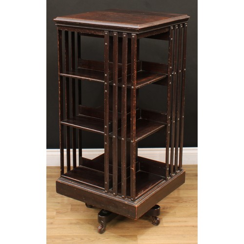 11 - An early 20th century oak revolving bookcase, moulded top above an arrangement of partially-slatted ... 