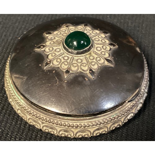 50 - A Middle Eastern silver circular box, applied with filigree, hinged cover centred by a cabochon, the... 
