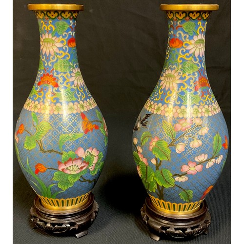 32 - A pair of Chinese cloisonne bottle vases, decorated with pink blossom on a blue ground, carved woode... 