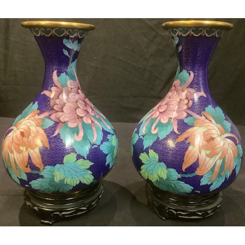 23 - A pair of Chinese cloisonne bottle vases, applied with bold pink flower heads on a cobalt blue groun... 