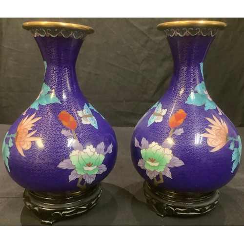 23 - A pair of Chinese cloisonne bottle vases, applied with bold pink flower heads on a cobalt blue groun... 
