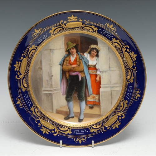 19 - A Vienna circular plate, painted with  Romany couple within a seed pearl gilt border, the cobalt blu... 