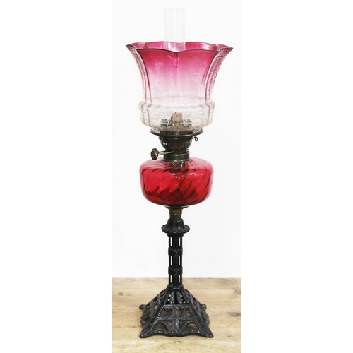 56 - A Victorian cast iron oil lamp with ruby glass reservoir and etched cranberry glass shade, height 68... 