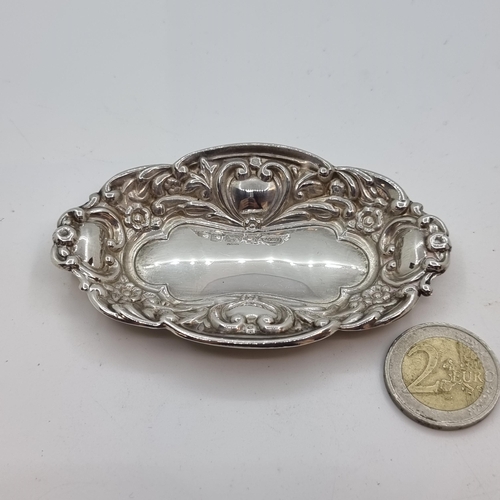 34 - A sterling silver pin dish with shield and foliate design. Hallmarked Birmingham 1992, maker W I Bro... 