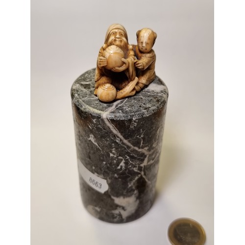 36 - Two items, including a finely carved Netsuke fukurokuju and child figure and a cylindrical marble ba... 
