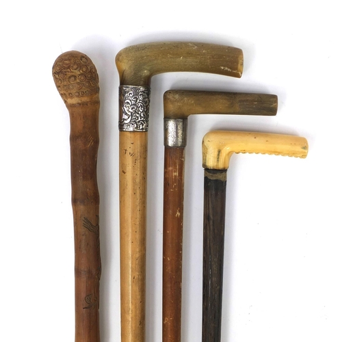 32 - Four wooden walking sticks comprising two with silver collars and horn handles, one with ivory handl... 
