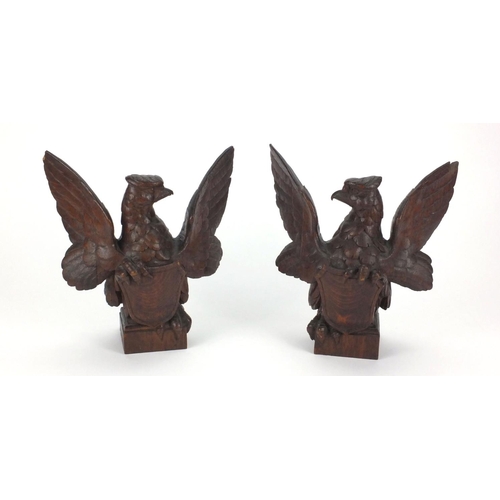 38 - Pair of carved wooden phoenixes with heraldic  shields on square bases, each 23.5cm high