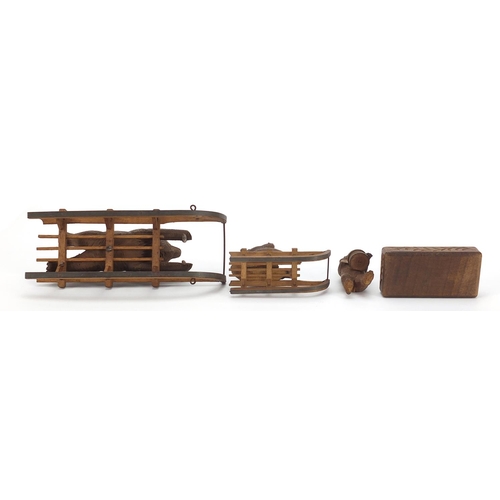 15 - Three carved Black Forest bears and a matchbox including two riding sleds, the largest 15cm in lengt... 