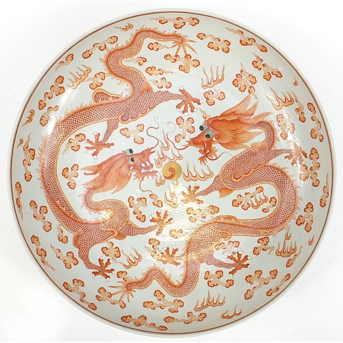 31 - Large Chinese porcelain charger hand painted in iron red with two dragons chasing a flaming pearl am... 