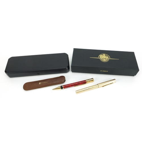 54 - Parker Duofold red marbleised propelling pencil with case and a gold plated bark design fountain pen... 