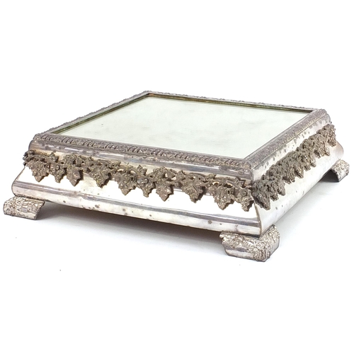 55 - Square silver plated mirrored cake stand relief decorated with grapes on a vine, housed in a painted... 