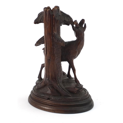 49 - Carved Black Forest spill vase in the form of a deer beside a trunk, 21cm high