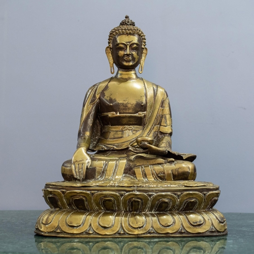 A Patinated Bronze Figure of the Buddha, seated on a double-lotus throne, the body clad in flowing robes tied at the waist with a bowed sash, the torso exposed, the serene face with downcast eyes, the right hand touching the earth, the left holding a bowl 69cm high