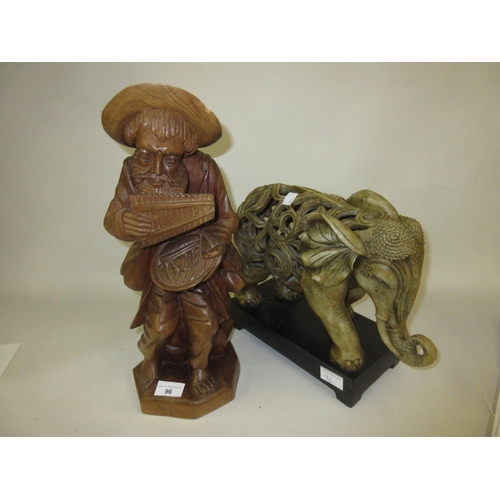 96 - Carved wooden figure of a seated man, together with a ceramic figure of an elephant