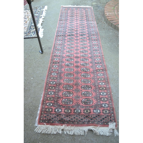 29 - Pakistan runner of Bokhara design with two rows of gols on a pink ground, 10ft x 2ft 10ins approxima... 