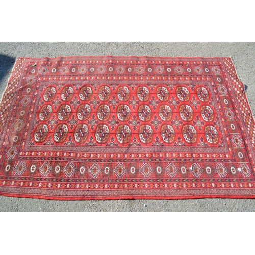 35 - Pakistan rug of Bokhara design with three rows of gols on a wine red ground, 6ft 4ins x 4ft approxim... 