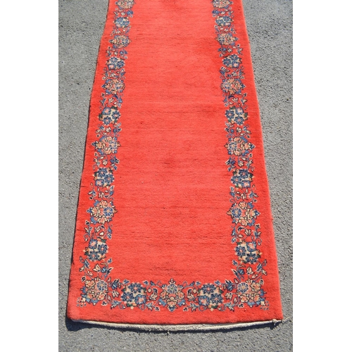 37 - Unusual mid 20th Century central Persian runner, the plain red field with a repeating floral border,... 