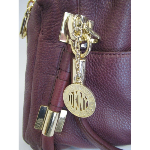 40A - DKNY burgundy leather handbag with gold tone hardware, together with a Michael Kors silver leather c... 