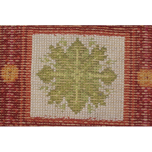 24 - Flatweave woollen rug with an all-over panel design in shades of red, green and cream, 10ft 6ins x 5... 